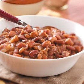 Picture of a white bowl filled with Wood's smoky baked beans and a spoon in them.