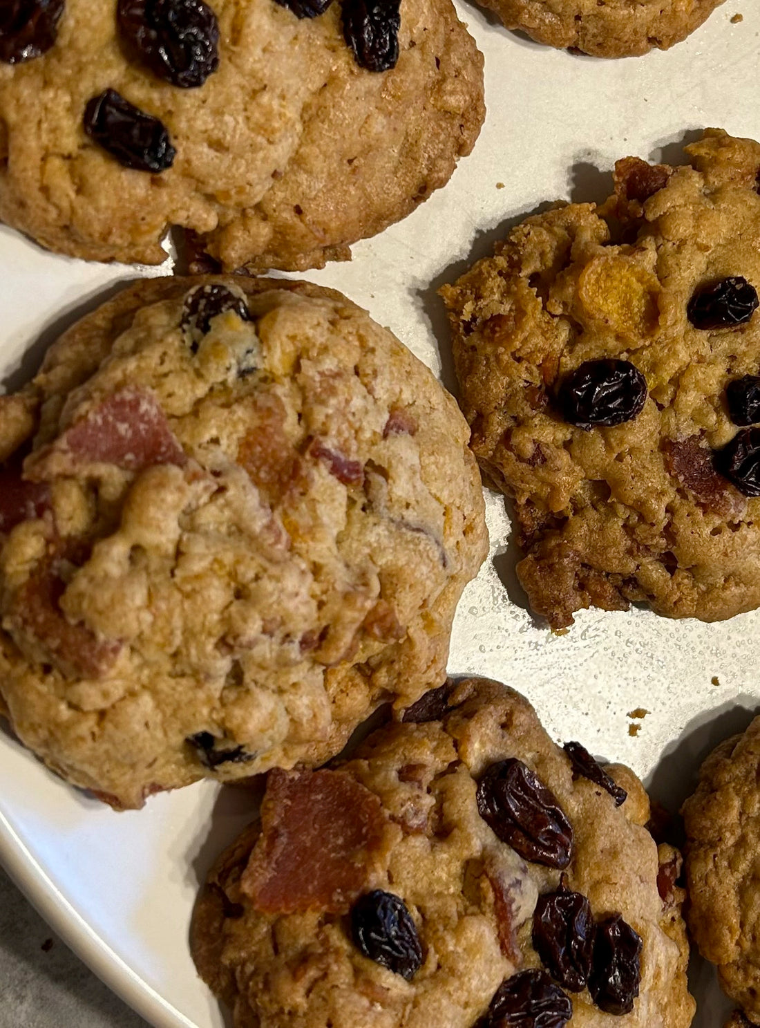 Brown Bacon Breakfast Cookies spotted with raisins and bits of bacon on a cutting board.  